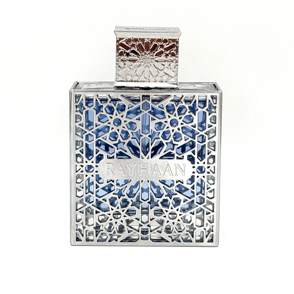 A square-shaped Rayhaan perfume bottle with a silver-toned geometric filigree frame and blue faceted crystals inside, set against a plain white background.